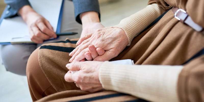 Foco nas mãos de uma idosa recebendo atendimento psicológico. Imagem para ilustrar a matéria sobre a nova Caderneta da Pessoa Idosa.
