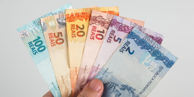 Uma mão segurando notas de dinheiro, representando a matéria sobre o salário médio dos brasileiros.