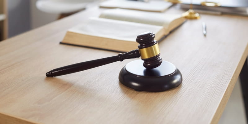 Foto do local de trabalho do juiz com martelo e escamas em uma mesa de madeira. Imagem para ilustrar a matéria sobre a tese da revisão da vida toda.