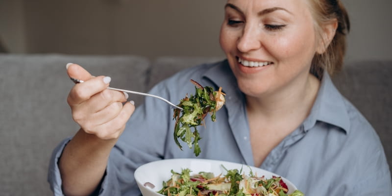 Uma mulher comendo uma salada com alimentos bons para o intestino.