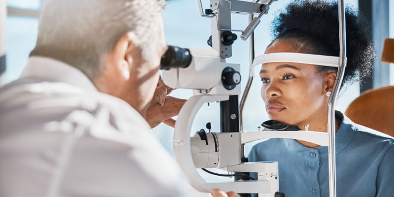 Uma mulher negra e jovem fazendo exame de vista para identificar glaucoma.