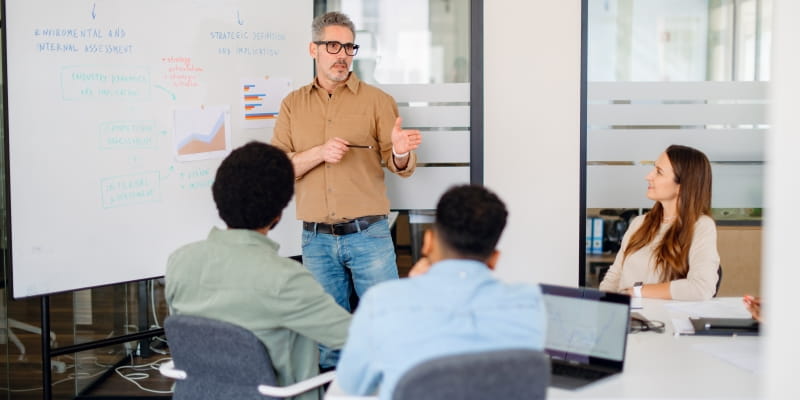Líder sênior de negócios que oferece uma apresentação estratégica para uma equipe diversificada e engajada, ilustrando a matéria sobre portfolio career.