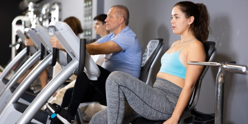 Pessoas de diferentes idades fazendo exercício em atividade física em uma academia, como prevenção à demência.