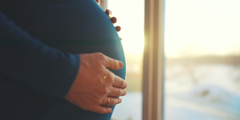 Zoom na barriga de uma mulher grávida, representando a matéria sobre longevidade feminina.