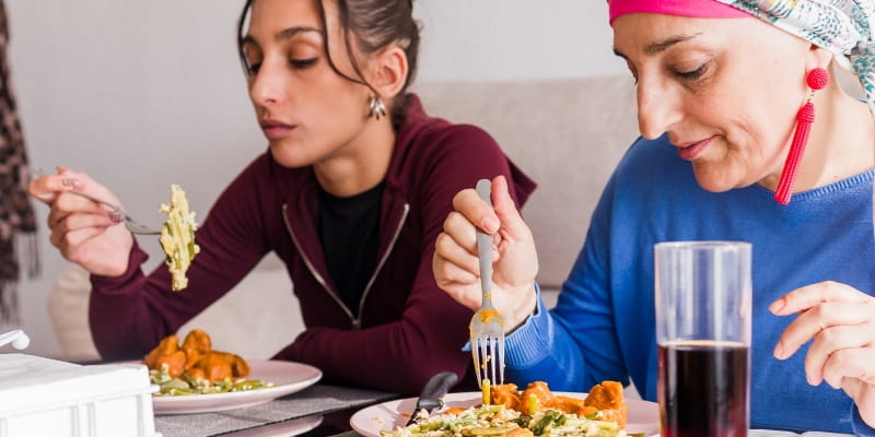 Mãe e filha almoçando durante a recuperação do câncer. Imagem para ilustrar a matéria sobre alimentação no tratamento do câncer de mama.