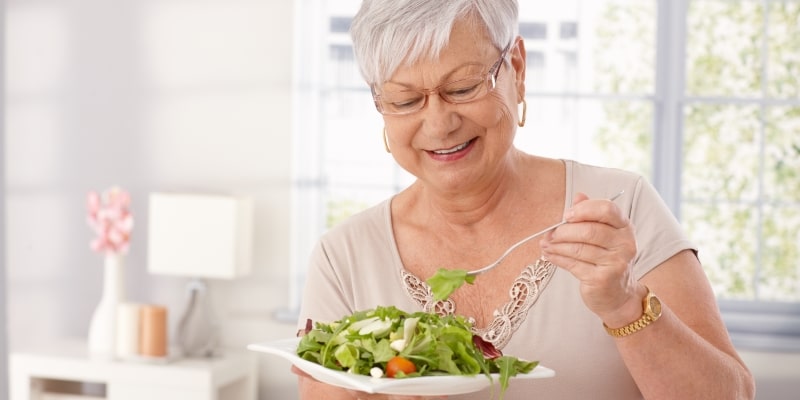 Uma mulher idosa comendo salada. Imagem para ilustrar a matéria sobre ganho de peso.