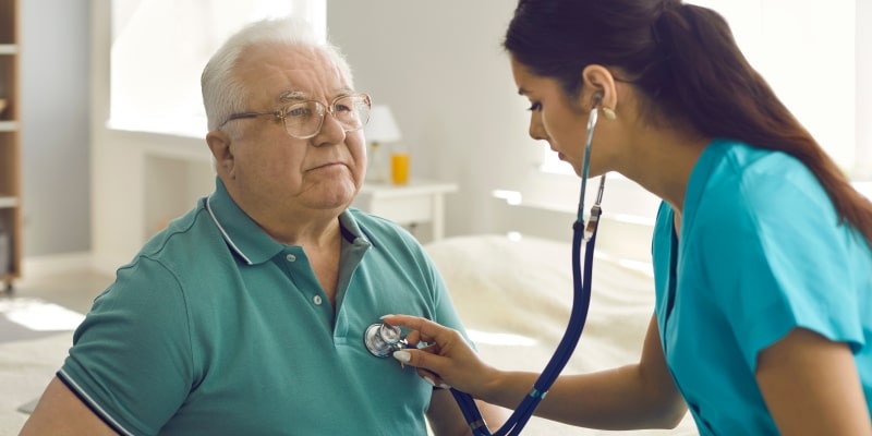 Um senhor idoso, com obesidade ou sobrepeso, sendo avaliado por uma enfermeira.